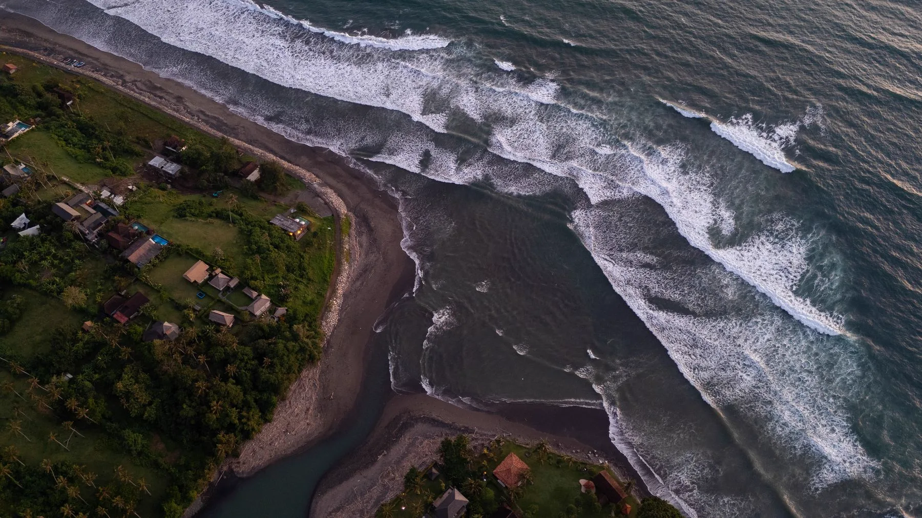 Desembocadura del río y playa de arena volcánica en la costa oeste de Bali, vista cenital