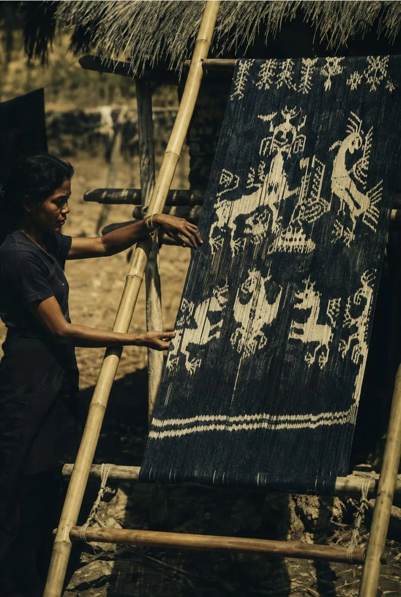 Sumba weaver beside a traditional ikat textile